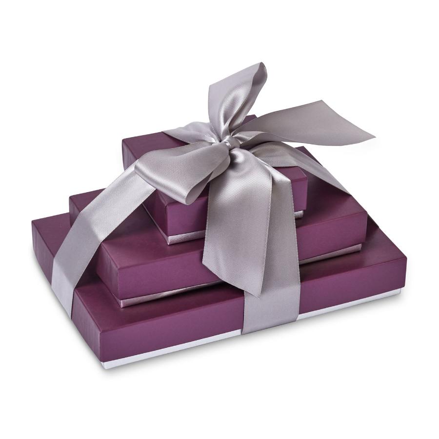 3 plum colored chocolate boxes are stacked on each other from smallest to largest on a white background. The boxes are tied together with a wide silver satin ribbon, tied into a bow.