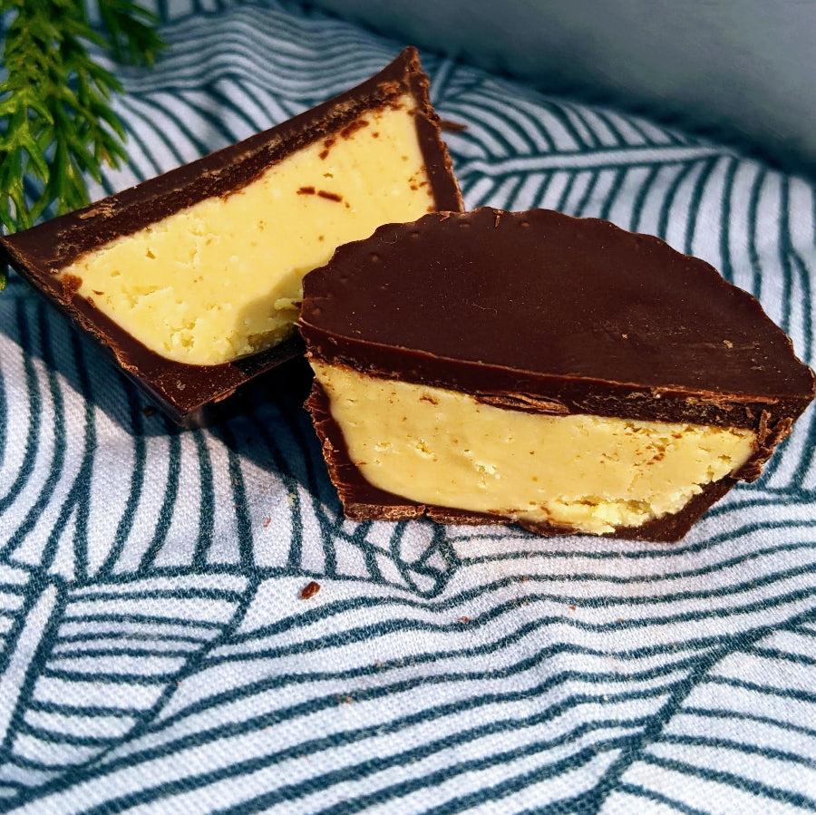 A chocolate covered peanut butter cup is cut open showing a peanut butter ganache filling inside.