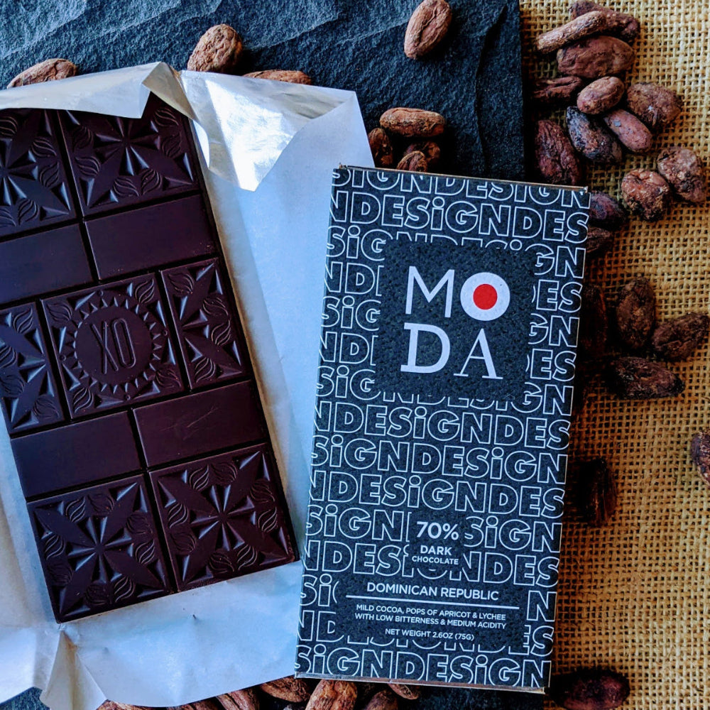 An unwrapped Xocolatl Chocolate bar beside its wrapper that's branded MODA, the Museum of Design Atlanta.