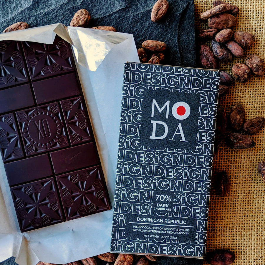An unwrapped Xocolatl Chocolate bar beside its wrapper that's branded MODA, the Museum of Design Atlanta.
