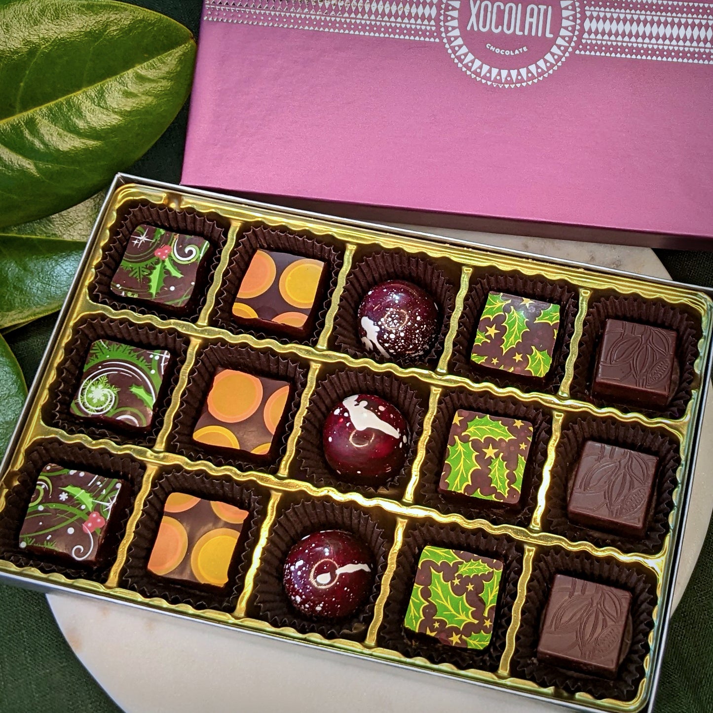 Box of assorted chocolates with a purple Xocolatl box in the background